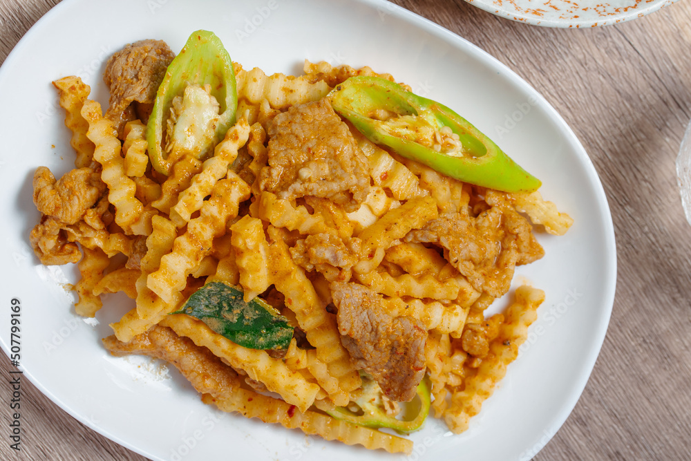 Stir-fried pork with red curry paste and young coconut shoots in a white plate Stir-fried pork with red curry paste and young coconut shoots in a white plate