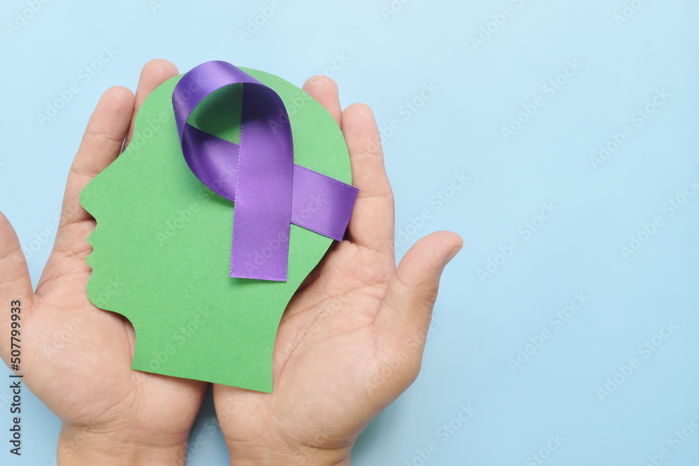 Hand holding human head profile with purple awareness ribbon on brain. Alzheimer's Disease, ADHD, ADD, Epilepsy, Cystic Fibrosis, Thyroid and Pancreatic Cancer prevention concept.