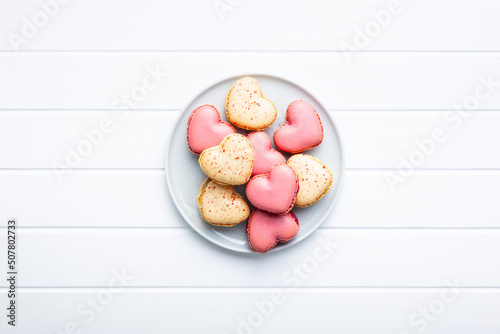 Heart shaped Sweet macarons on plate on white table.