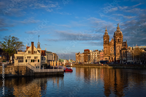 Amsterdam canal and Church of Saint Nicholas (Sint-Nicolaaskerk) on sunset. View from Amsterdam Centraal. Amsterdam, Netherlands