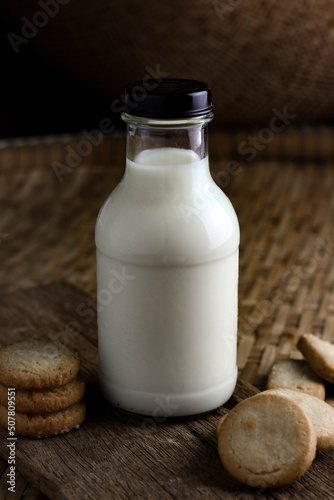 glass of milk and cookies with wooden background