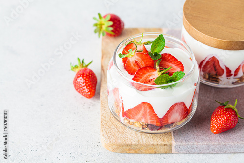 Strawberry parfait with yogurt and granola in glass jar. Healthy breakfast recipe. Summer dessert concept.