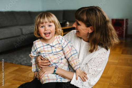 Portrait of happy daughter with mother sitting in living room at home photo