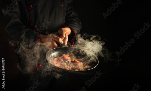 Fototapeta Naklejka Na Ścianę i Meble -  Cooking vegetables on a hot frying pan in the hands of a chef. Molecular gastronomy or cuisine