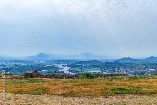 The ruins of the fortress wall of Rozafa Castle against the backdrop of the Drin river valley, Albania. Beautiful landscape on a summer cloudy day