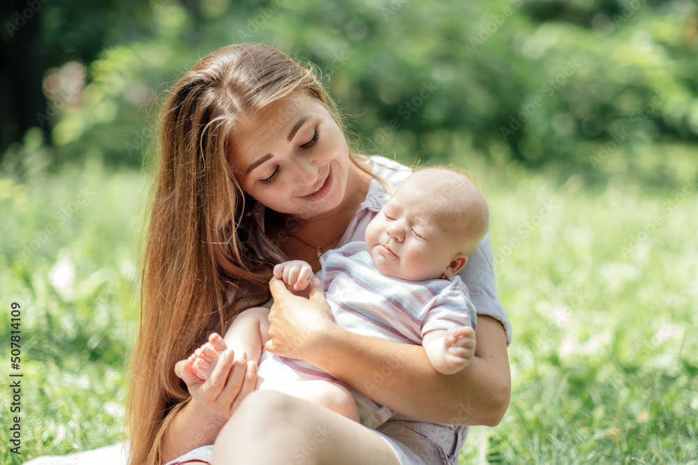 Newborn baby spending time outside. Happy and smiling mother with her newborn baby spending time in the park. Getting fresh air and natural sunlight for babies. Newborn baby spending time outside. Happy and smiling mother with her newborn baby spending time in the park. Getting fresh air and natural sunlight for babies.