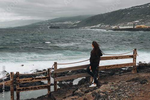 Girl stand near stormy sea in Tenerife, Spain