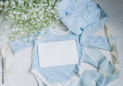 postcard mockup on the background of baby newborn clothes in blue colors