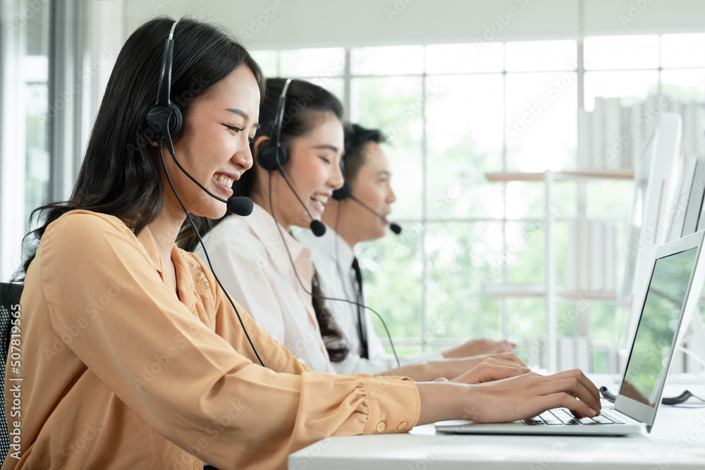 Group of Asian employee work in telemarketing customer service teams. Young operator woman working with headset smiling and doing customer support at work. Call Center with service mind concept Group of Asian employee work in telemarketing customer service teams. Young operator woman working with headset smiling and doing customer support at work. Call Center with service mind concept