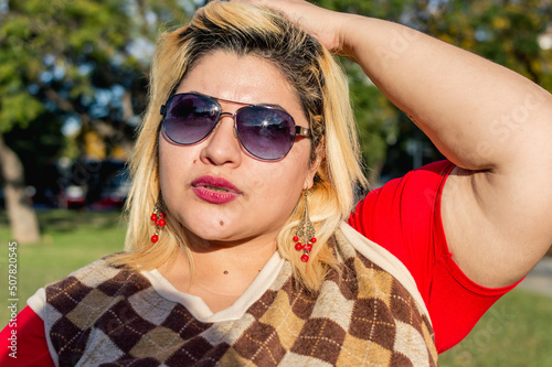 portrait young plus size latin woman outdoors looking at the camera with one hand on her head