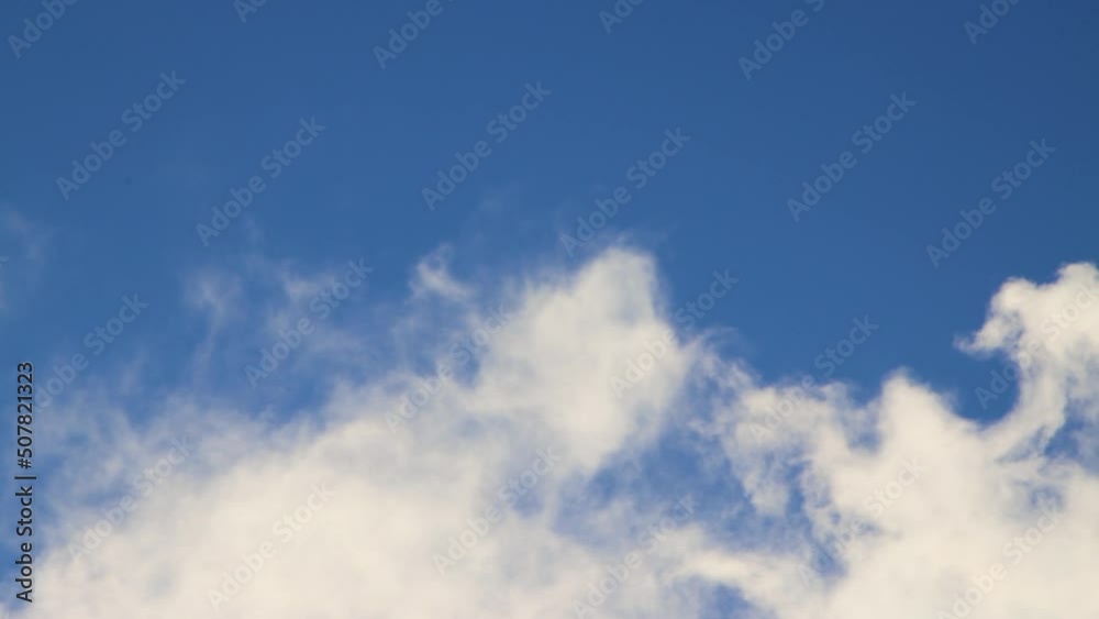A white fluffy cloud is moving fast against a blue sky. Summer or winter time lapse, clear sky, warm light, panorama. Video, screensaver background, for titles, intro, transition. UHD 4K. A white fluffy cloud is moving fast against a blue sky. Summer or winter time lapse, clear sky, warm light, panorama. Video, screensaver background, for titles, intro, transition. UHD 4K.