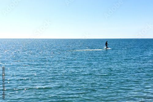 Man surfing on hydrofoils. Silhouette on the background of the sea surface on a bright sunny day © Maksim