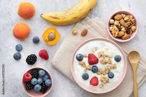 Concept of healthy nutrition. Food for breakfast, top view, a bowl with low-fat yogurt, crunchy oatmeal, dried and fresh fruit.