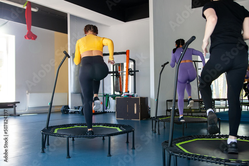 Four young women on trampoline, young fitness girls trains on   fitness studio. photo