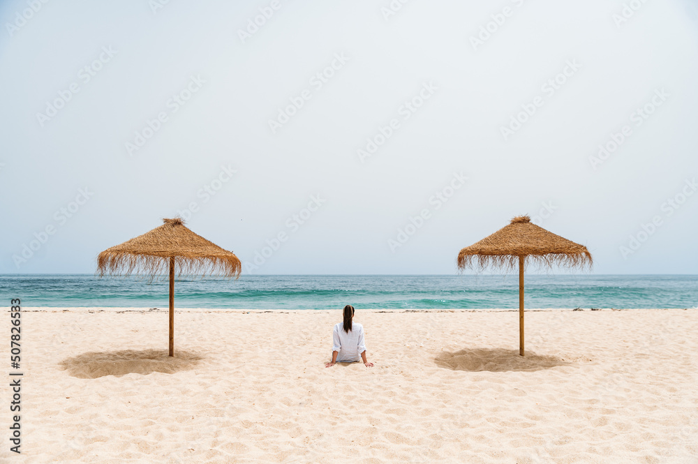 Fototapeta premium Female traveler sitting on sand near ocean