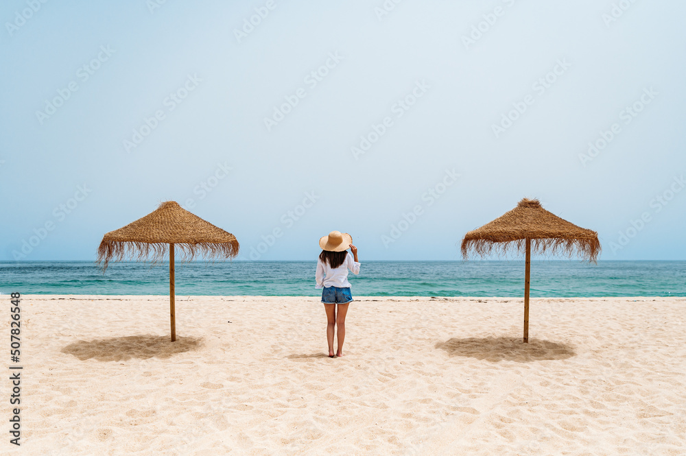Female traveler standing on sand near ocean