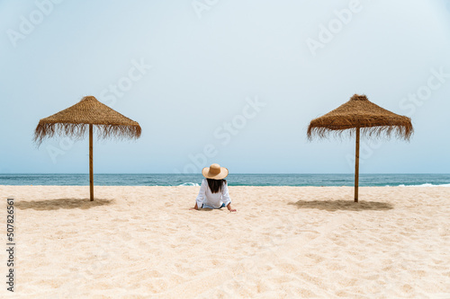 Female traveler sitting on sand near ocean