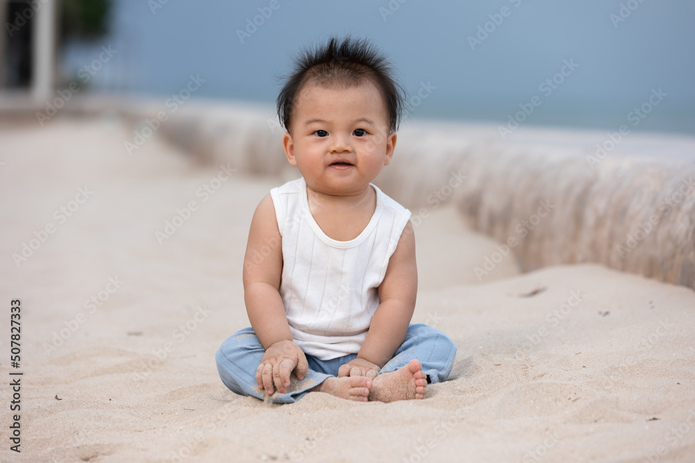 Adorable asian baby sit on sand spend time to learn all around beach and sea. First time to touch sand of cute baby infant excite and happiness. Little baby boy playing outdoor and looking at camera Adorable asian baby sit on sand spend time to learn all around beach and sea. First time to touch sand of cute baby infant excite and happiness. Little baby boy playing outdoor and looking at camera