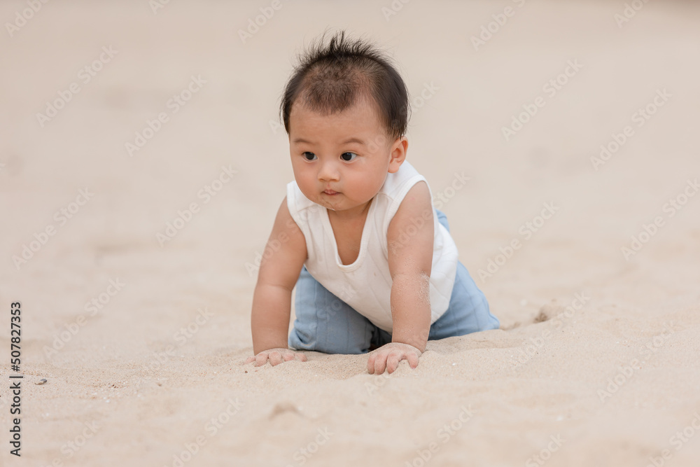 Healthy asian baby toddler crawling on the beach to learn to crawl outdoors. Adorable baby keeping her belly and legs down on sand to belly crawl fun and happiness at home. Baby growth concept Healthy asian baby toddler crawling on the beach to learn to crawl outdoors. Adorable baby keeping her belly and legs down on sand to belly crawl fun and happiness at home. Baby growth concept