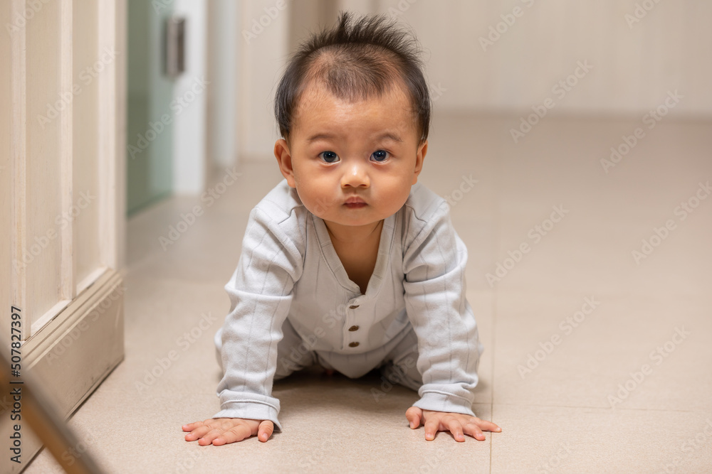 Healthy asian baby toddler crawling on floor to learn to crawl indoors. Adorable baby keeping her belly and legs down on the floor to belly crawl fun and happiness at home Healthy asian baby toddler crawling on floor to learn to crawl indoors. Adorable baby keeping her belly and legs down on the floor to belly crawl fun and happiness at home