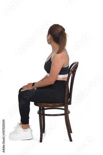 full view of a woman sitting on chair and looking backwards on white background