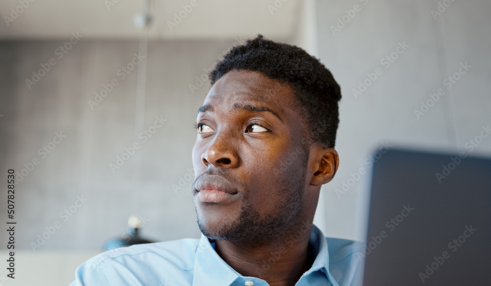 Portrait of young african american man in living room using laptop