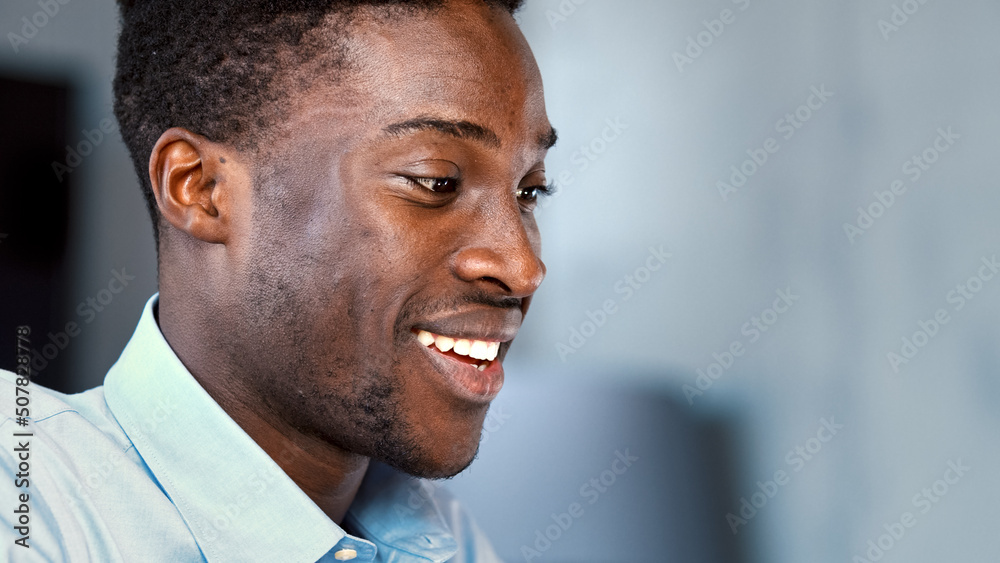 Young smiling guy typing on laptop keyboard