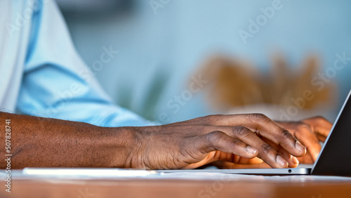 Hands of a young man typing on a laptop keyboard