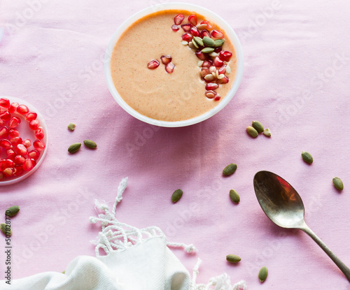 Overhead view of a bowl of fresh vanilla flavored custard pudding or mousse with pomegranate seeds topping and isolated on light background. Copy space 