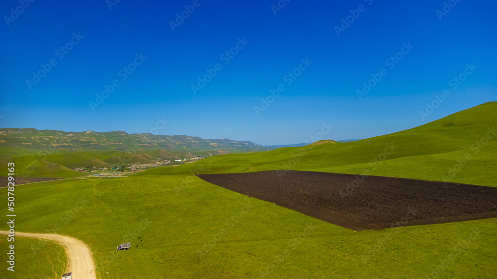 Fototapeta premium Top view from a drone on mountain pastures and road