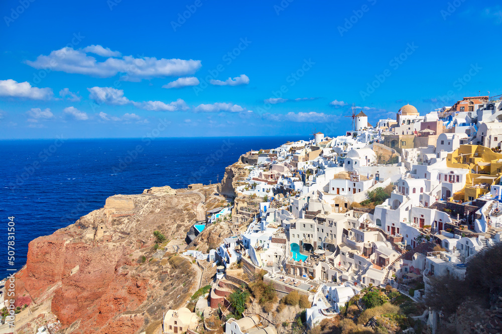 Greece vacation background. Famous iconic Oia village with traditional white houses and windmills during summer sunny day. Santorini island, Greece.