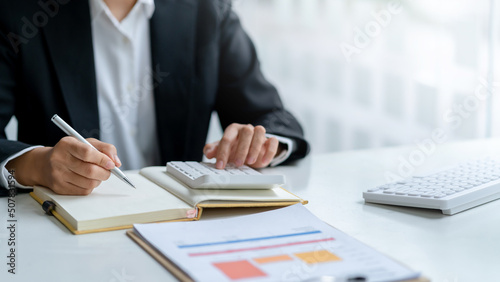 Close-up of businesswoman hands using a calculator to check company finances and earnings and budget. Business woman calculating monthly expenses, managing budget,  papers, loan documents, invoices. © amnaj