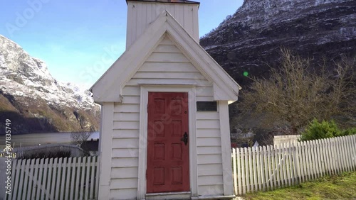 Tiny old historic stave church in Undredal Norway - Walking towards entrance with blue sky and mountain background photo