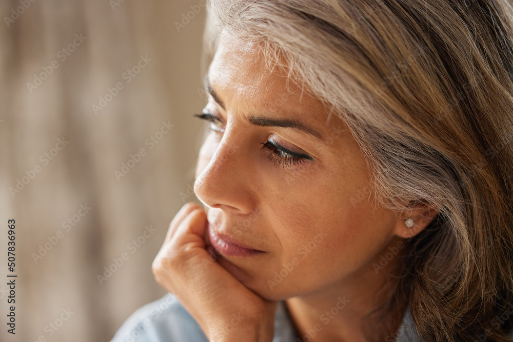 Naklejka premium Close Up Shot Of Thoughtful Mature Woman Looking Out Of Window At Home