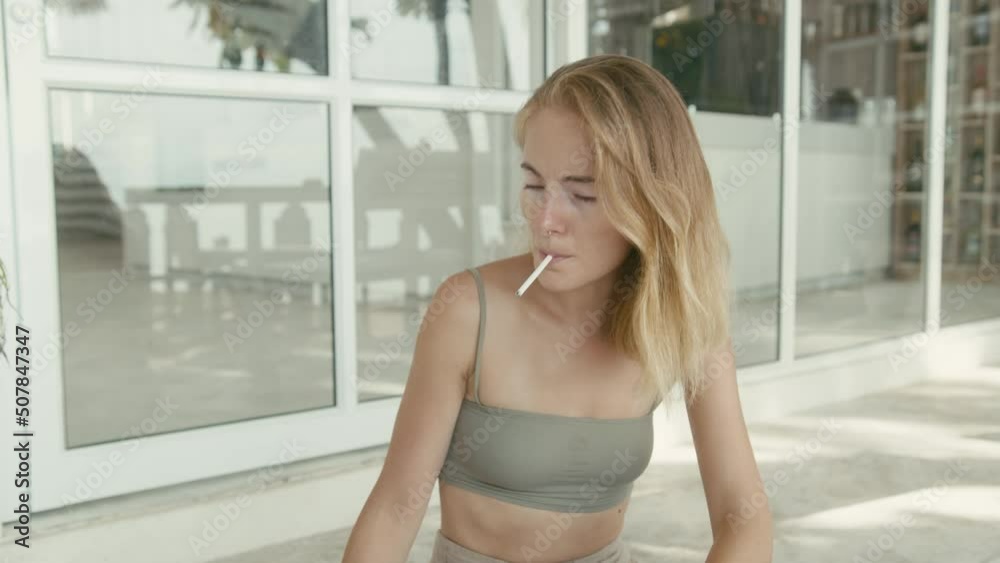 Pretty young woman with vitiligo pigmentation sits on the stairs and smokes 