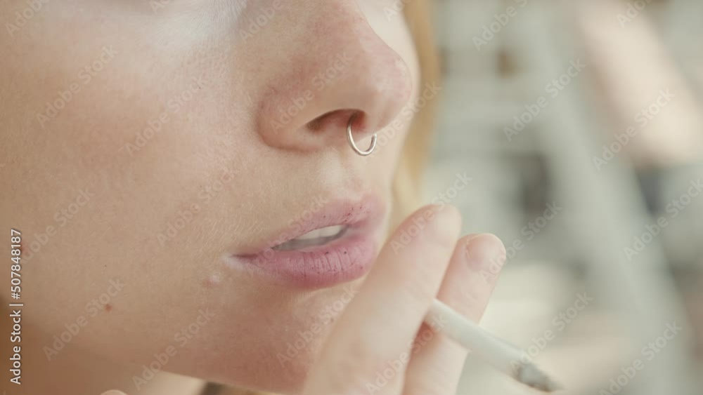 Pretty young woman with vitiligo pigmentation sits on the stairs and smokes 