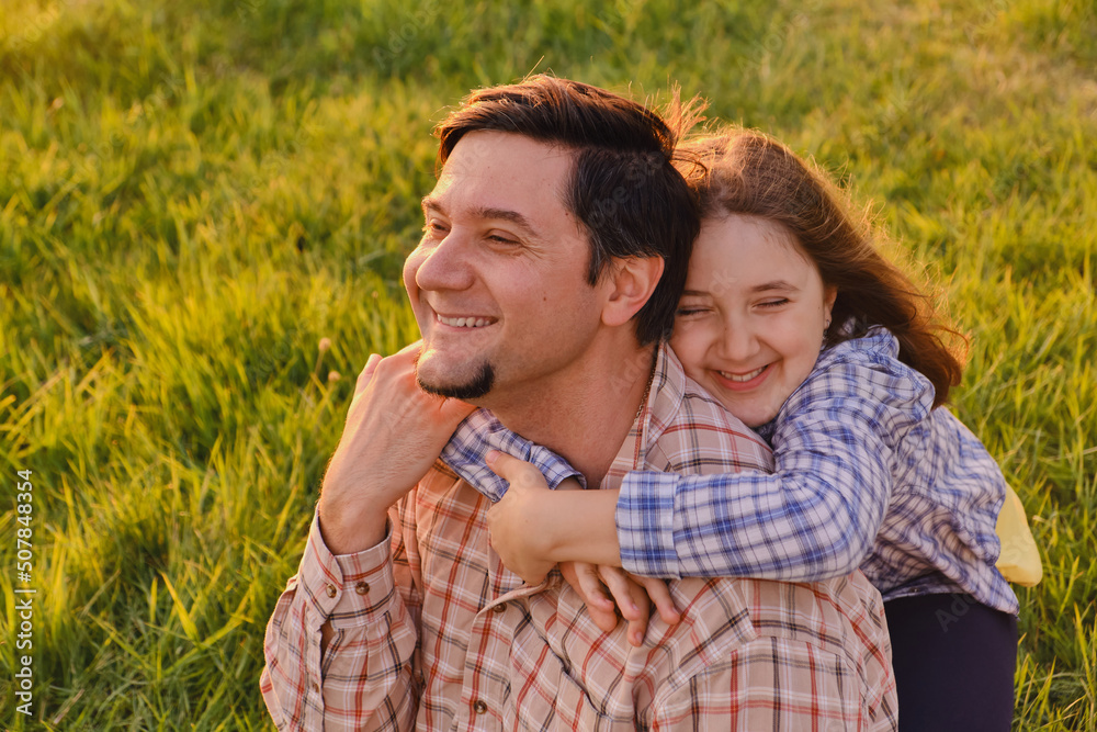 Fototapeta premium Smiling little girl hugging her father outside