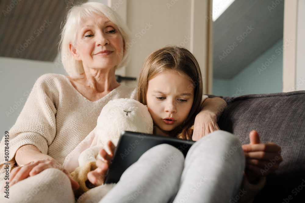 Happy grandmother and granddaughter using tablet computer at home Happy grandmother and granddaughter using tablet computer at home