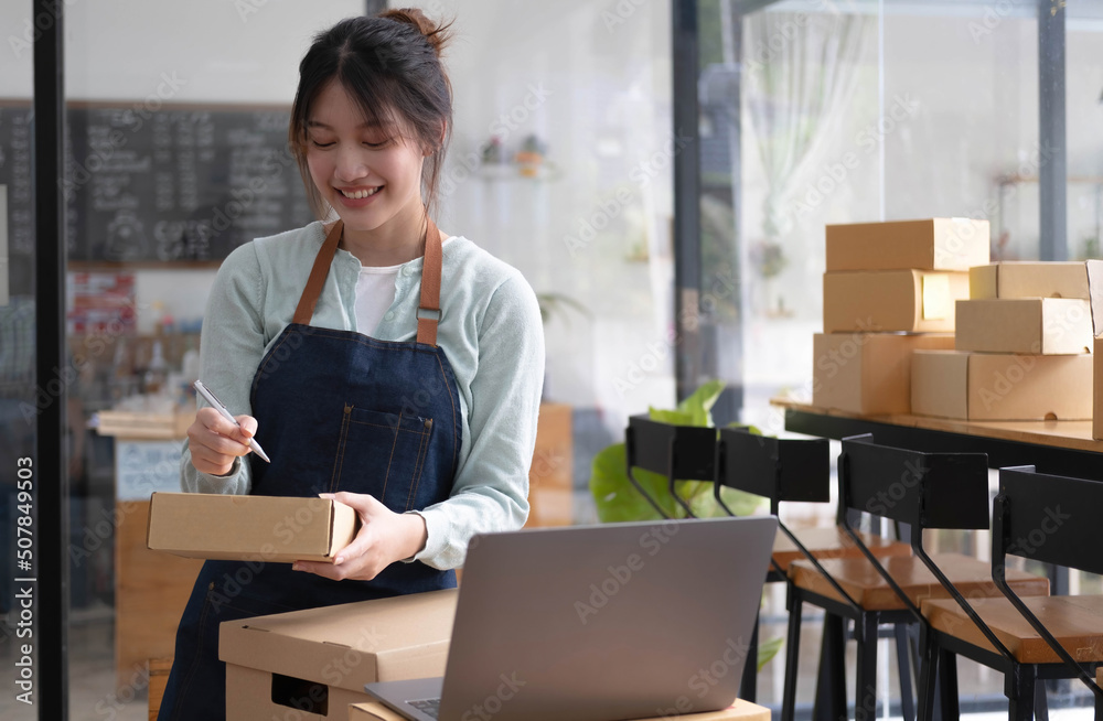 Shipping shopping online ,young start up small business owner writing address on cardboard box at workplace.small business entrepreneur SME or freelance asian woman working with box at home Shipping shopping online ,young start up small business owner writing address on cardboard box at workplace.small business entrepreneur SME or freelance asian woman working with box at home