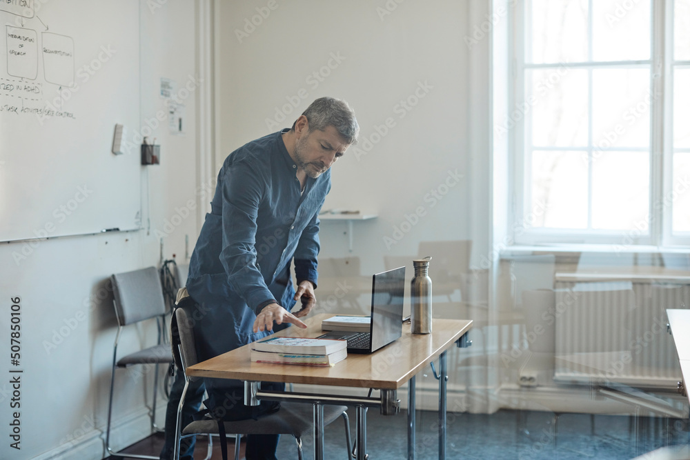 Male teacher arranging desk in university classroom Male teacher arranging desk in university classroom