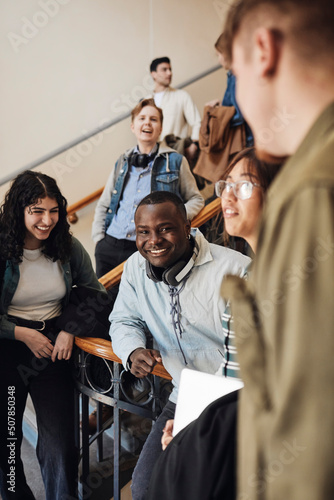 Happy young multiracial students enjoying at staircase in university photo