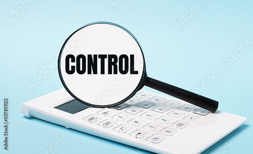 On a blue background, a white calculator and a magnifying glass with the text CONTROL. Business concept