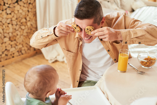 Happy moment, father and son have breakfast with cookies.