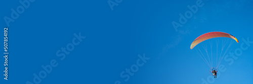 paraglider on a blue background, colorful canopy