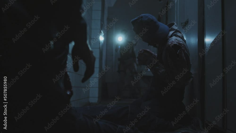 Low angle of two creepy zombies eating flesh on floor, then spotting and following female soldier with shaved head who holding flashlight, inspecting dark abandoned building Low angle of two creepy zombies eating flesh on floor, then spotting and following female soldier with shaved head who holding flashlight, inspecting dark abandoned building