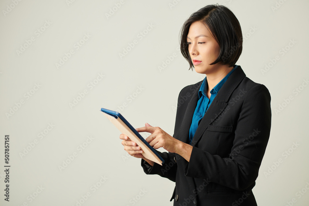 Serious female entrepreneur checking documant on tablet computer Serious female entrepreneur checking documant on tablet computer