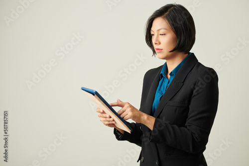 Serious female entrepreneur checking documant on tablet computer photo