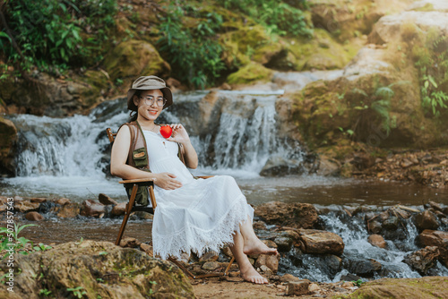 pregnant woman sitting at the waterfall