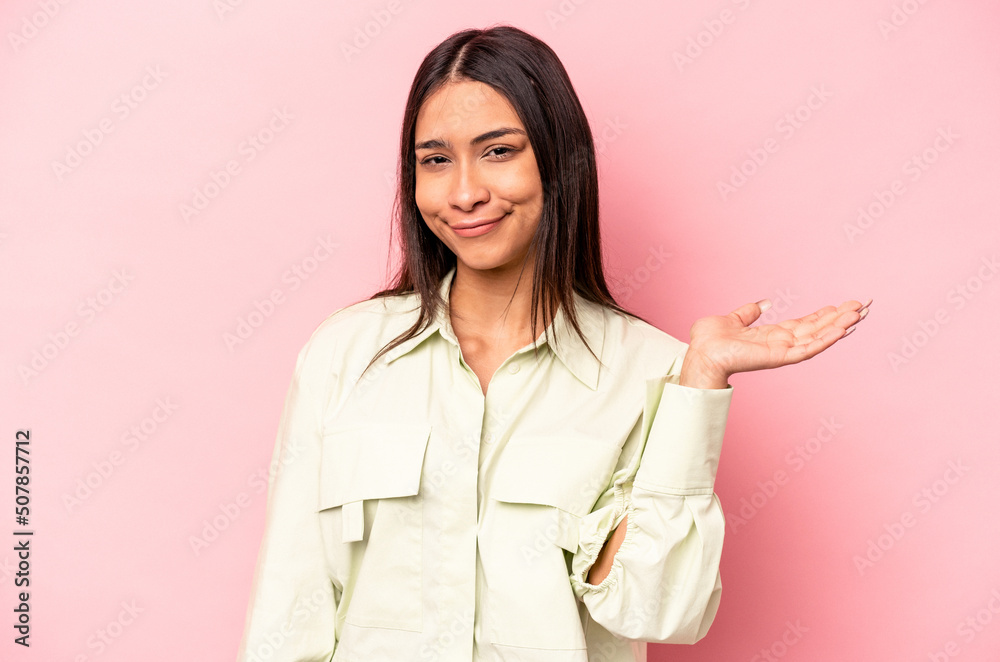 Young hispanic woman isolated on pink background doubting and shrugging shoulders in questioning gesture. Young hispanic woman isolated on pink background doubting and shrugging shoulders in questioning gesture.