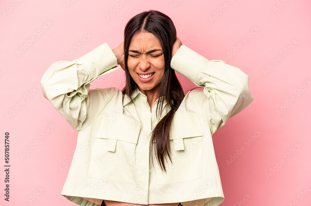 Young hispanic woman isolated on pink background covering ears with hands. Young hispanic woman isolated on pink background covering ears with hands.